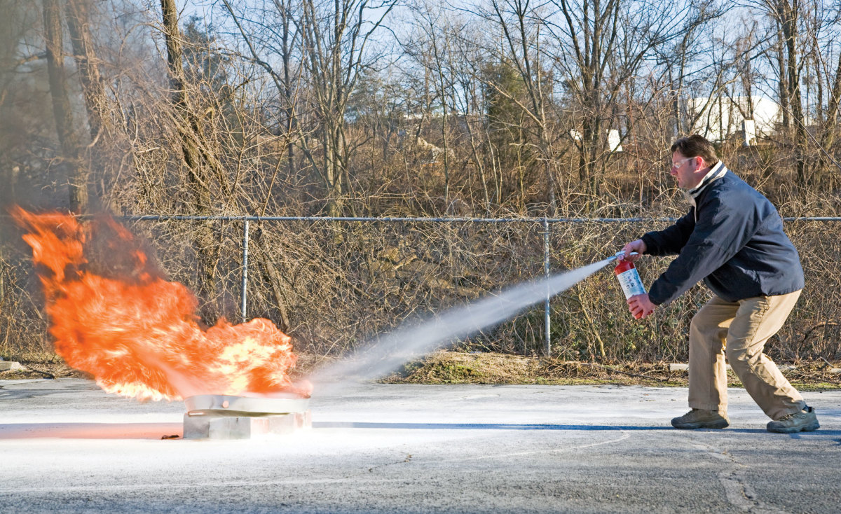Trialing a Halotron I extinguisher: note how the operator is aiming at the base of the flames