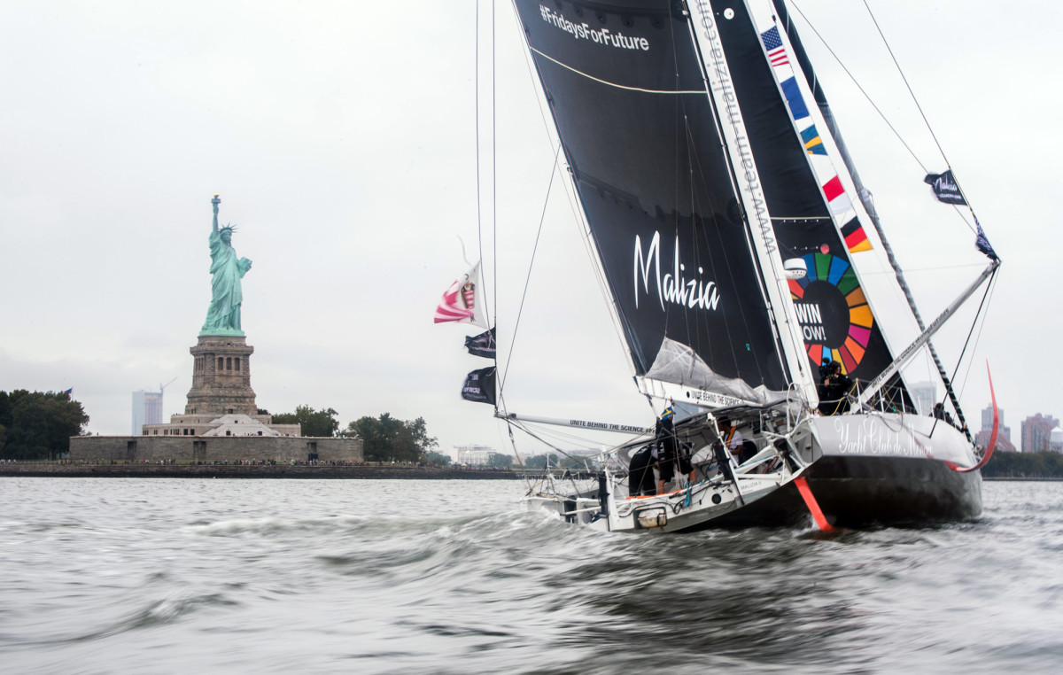 The IMOCA 60 Malizia II powers her way past the Statue of Liberty in the final moments of the passage