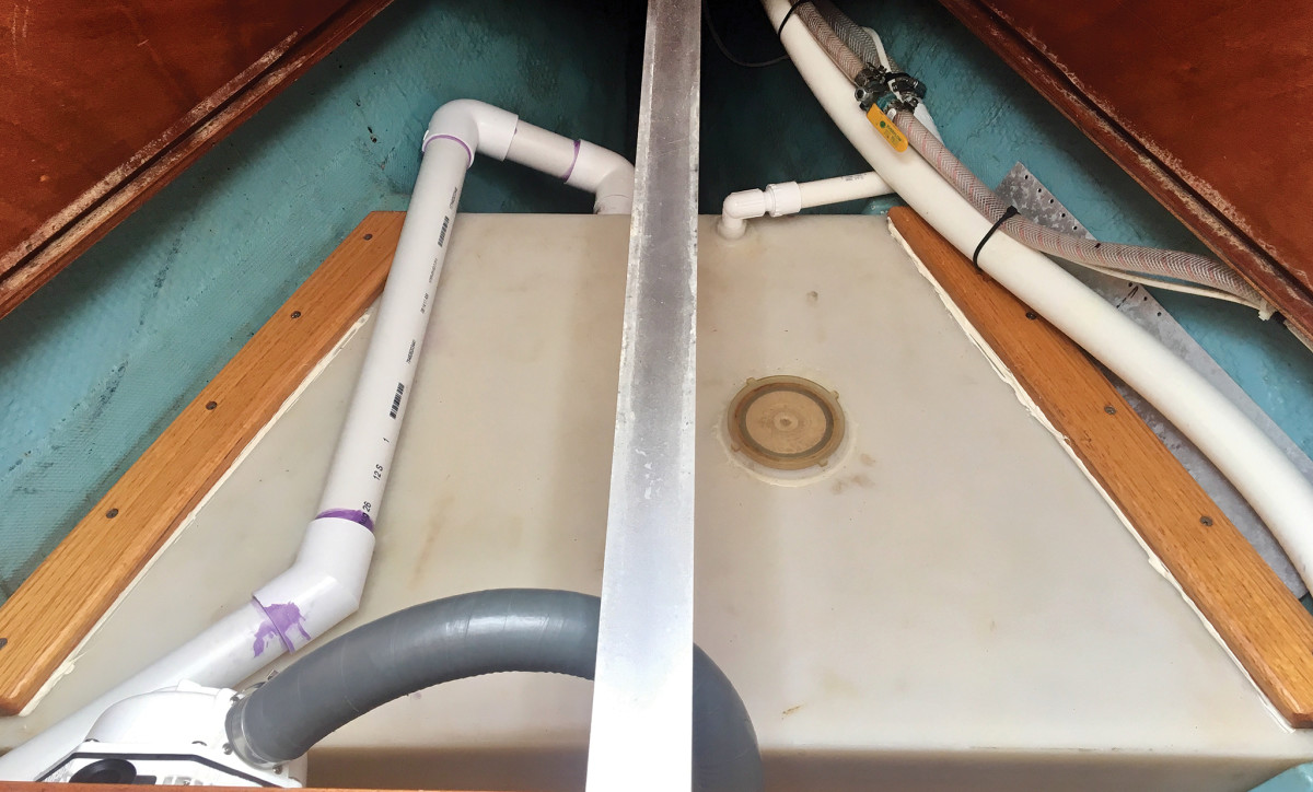 The V-berth holding tank re-plumbed with rigid PVC pipe and the manual discharge pump in the foreground