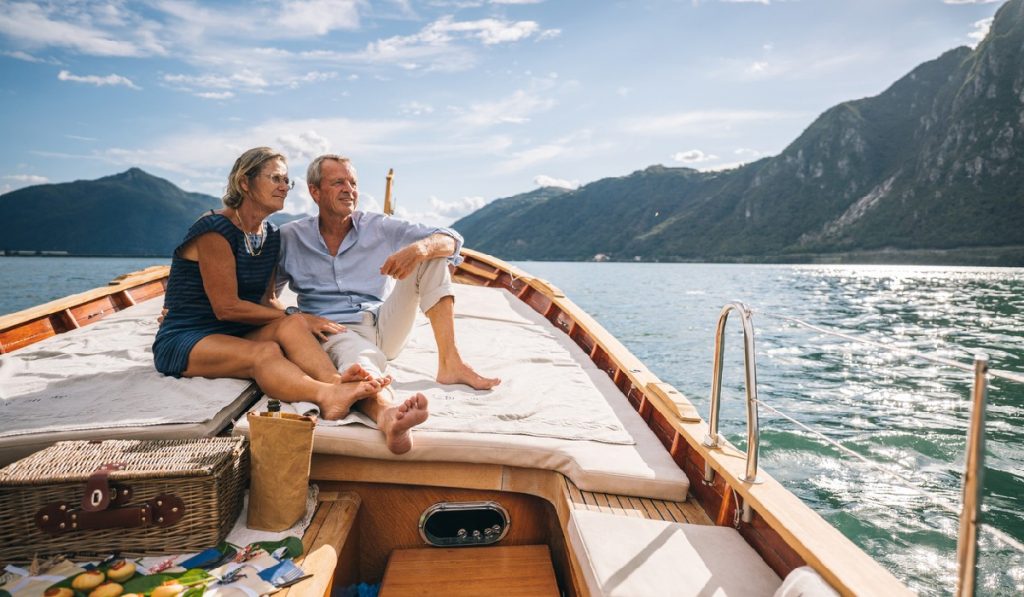 Mature couple relax on sailboat moving through Lake Lugano