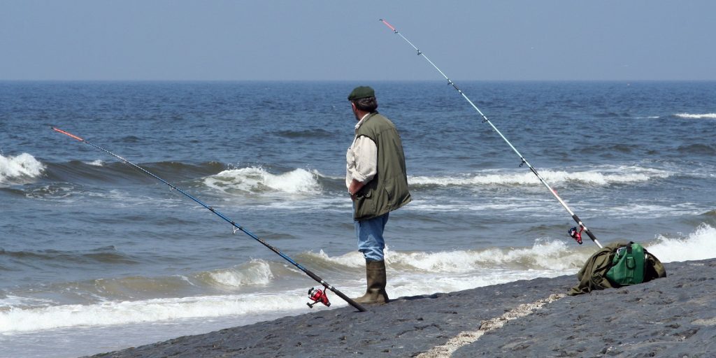 Standing fisherman with two rods, fishing in the sea