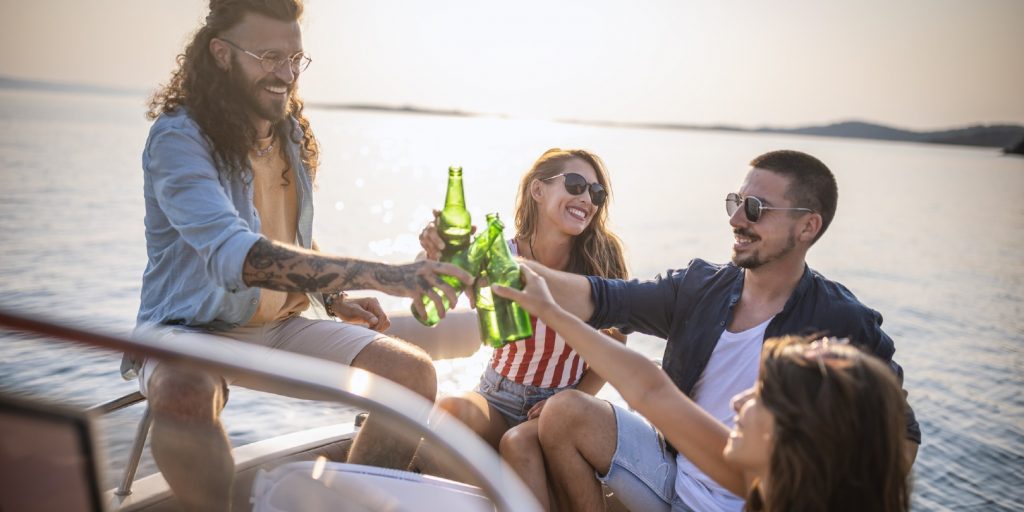 Photo of friends taking a boat trip during summer vacation, they relax and enjoy drinks.