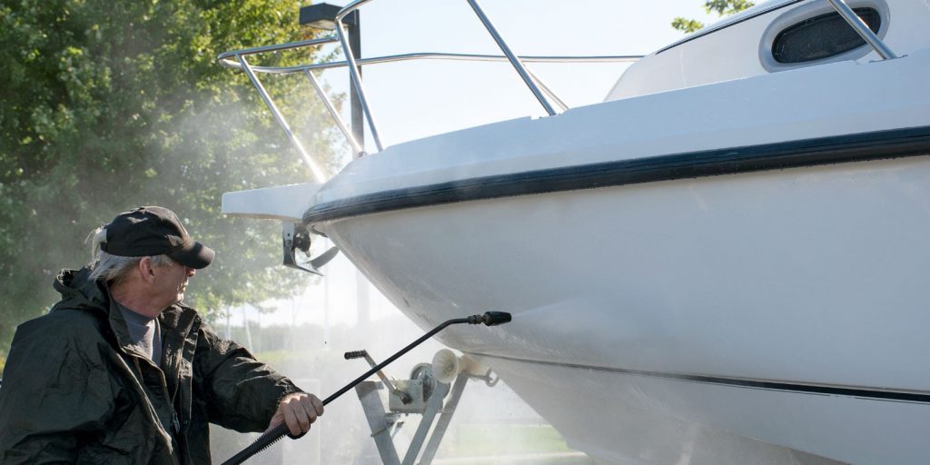 Caucasian man using pressure washer to clean boat hull