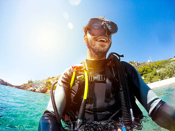 Young diver smiles while preparing for diving. He is wearing a wetsuit for diving.