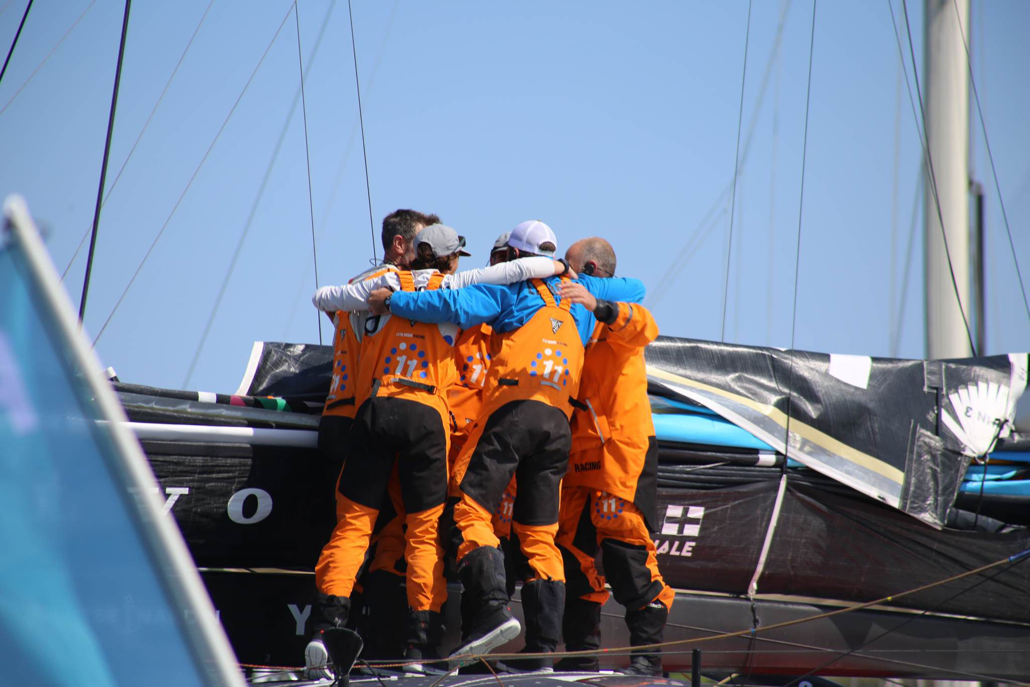 11th Hour Racing Team hugs at the end of a leg in Newport